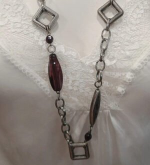 Collar largo plateado con detalles geométricos y cuentas burdeos