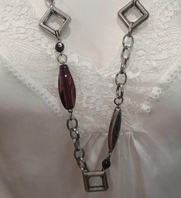 Collar largo plateado con detalles geométricos y cuentas burdeos